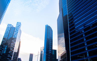 Bottom view of modern skyscrapers/office buildings in the business district of Singapore cities against the blue sky. Economy, finances, business activity concept.