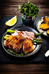 Grilled beefsteak with asparagus and baked potatoes on wooden background