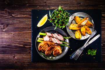 Grilled beefsteak with asparagus and baked potatoes on wooden background