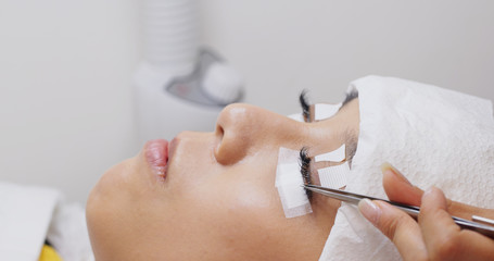 Woman having eyelash extension in beauty salon