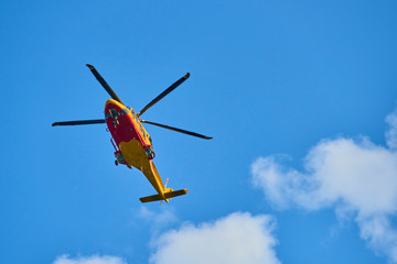 Fototapeta na wymiar Rescue helicopter moving in blue sky with blur propeller. View from bellow
