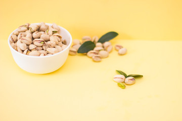 Salted pistachios in a bowl on a yellow background