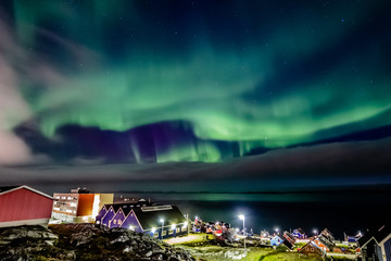 Green bright northern lights hidden by the clouds over the Inuit village at the fjord, Nuuk city, Greenland © vadim.nefedov