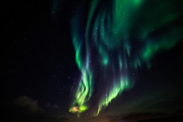 Massive green Aurora Borealis Northern lights shining over the lake and Nuuk city, Greenland