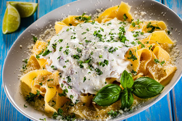 Tagliatelle with cream sauce and herbs on wooden table