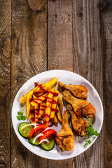 Grilled chicken drumsticks with french fries and vegetables