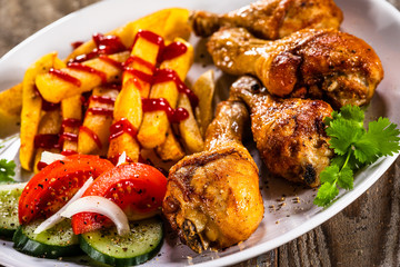 Grilled chicken drumsticks with french fries and vegetables