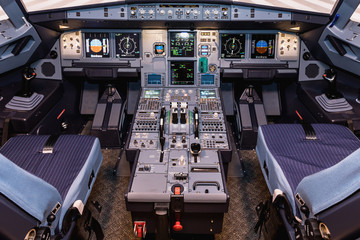 Cockpit of airliner simulator. Switches and dials visible in the background. - obrazy, fototapety, plakaty