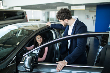 Plakat Successful young woman discussing her potential purchase with a car dealer