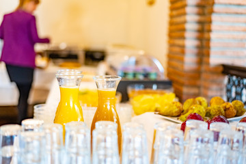 Orange juice glass bottles and some glasses with a breakfast buffet background, with narrow depth...