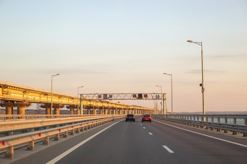 Fototapeta na wymiar motorway over the bridge with transport, on the right, the Crimean bridge under construction at dawn