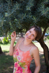 Outdoor portrait of a happy young woman under olive tree.