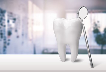 A white big tooth with dental mirror on the table in the doctor's office