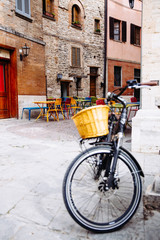 Vintage bicycle with basket standing on the street in city near the cafe