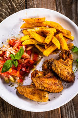 Grilled chicken wings, chips and vegetables