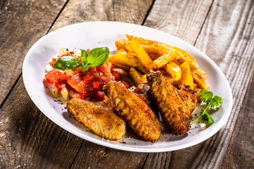 Grilled chicken wings, chips and vegetables