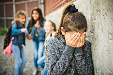 A sad girl intimidation moment on the elementary Age Bullying in Schoolyard - obrazy, fototapety, plakaty