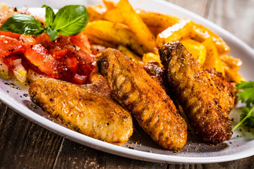 Grilled chicken wings, chips and vegetables
