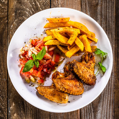 Grilled chicken wings, chips and vegetables