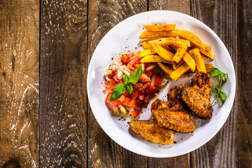 Grilled chicken wings, chips and vegetables