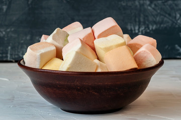 Aerial colorful marshmallow close-up. lies in pottery, plate. Marshmallow on dark grey retro background.  photo dessert with a place to copy space