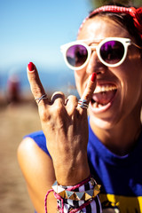 Pinup woman showing rock on hand with beautiful smile and wearing red nail polish, rings, bracelets...