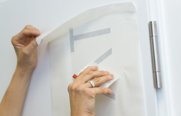 Folienschrift wird mit Übertragungspaier auf Türe verklebt