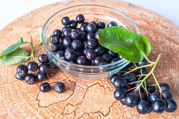 Aronia berries on a wooden background, cut logs. Vitamins and health.