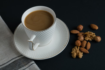 coffee in white cup with nuts dark background