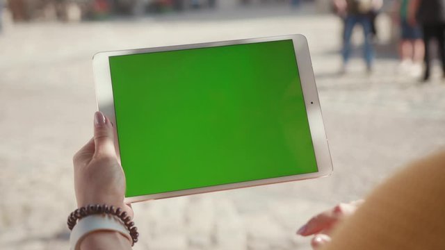 Close up hands woman using touch tablet device computer with green screen outdoors in street at sunlight horizontal message pad technology chroma key female digital girl app chat finger slow motion