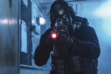 Special unit soldier with gas mask is going out of industrial elevator and aiming a target