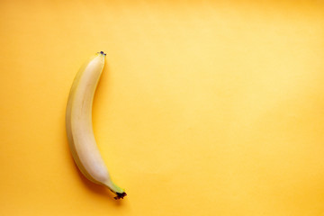 Banana lies vertically on a yellow background. Flat layout.