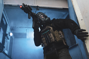 Special unit soldier with gas mask is going out of industrial elevator and aiming a target
