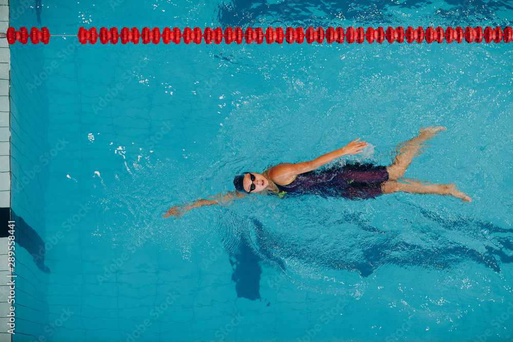 Wall mural Young woman swimmer swims in swimming pool