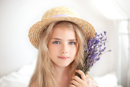 Closeup romantic portrait Charming little blond girl in a straw hat holds a bouquet of lavender. Summer flowers, aromatherapy. An allergy. Childhood concept. Girl holds a bouquet of lavender. provence