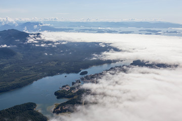 Aerial View of a Small Town, Ucluelet, on the Pacific Ocean Coast being Covered by Clouds during a sunny summer morning. Located on Vancouver Island, British Columbia, Canada.
