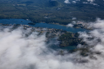 Aerial View of a Small Town, Ucluelet, on the Pacific Ocean Coast being Covered by Clouds during a sunny summer morning. Located on Vancouver Island, British Columbia, Canada.