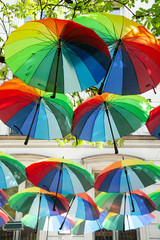 Decorative multicolored umbrellas in the center of Paris, Marais. Rainbow and multicolor as symbol of gay, lesbian, bisexual, transgenders. Colorful and beautiful composition. Trees with green leaves