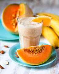 Summer smoothie: fresh melon, banana and almond milk. Healthy light food, vitamins and energy source. Served on mint blue plates. Contrast bright colors, vacations mode on