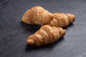 Fresh croissants on black slate background. Copy space