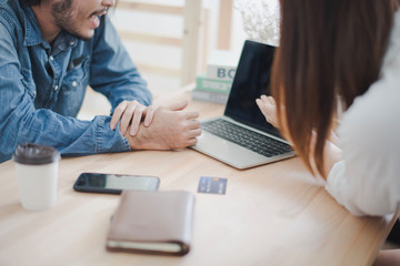 Young Asian man and woman are talking about business meeting and present by computer laptop in white room at office which glad smiling and felling happy.