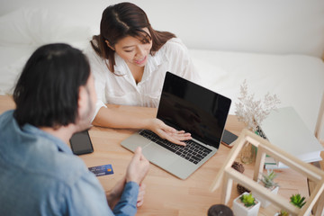 Young Asian man and woman are talking about business meeting and present by computer laptop in white room at office which glad smiling and felling happy.