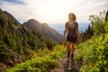 Fototapeta premium Adventurous girl hiking the beautiful trail in the Canadian Mountain Landscape during a vibrant summer evening. Taken at Mt Arrowsmith, near Nanaimo, Vancouver Island, BC, Canada.