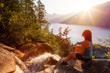 Adventurous Girl is sitting on top of a Beautiful Waterfall, Shannon Falls, and watching the...
