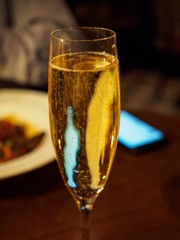 Close-up vertical detail of a glass of fizzy Champagne at a French bistro. London, United Kingdom. Travel, drinks, and cuisine.