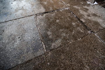 Obraz premium Wet surface of paving stones with pieces of ice