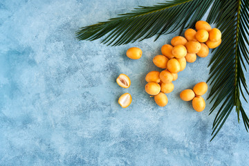 Fresh raw yellow dates with palm leaf on blue background. Top view