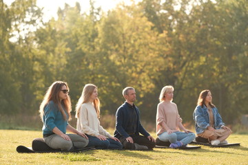 Group of young sporty people practicing yoga lesson with instructor, sitting in Sukhasana exercise, Easy Seat pose, working out, students training 