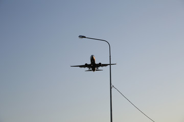 Airplane flies low over a city lighting lantern. The plane is landing. Air passenger transport.