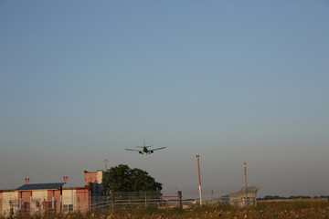 Obraz premium The plane lands at the airport at sunset. Landing strip and security zone of the airport. Air passenger transport.